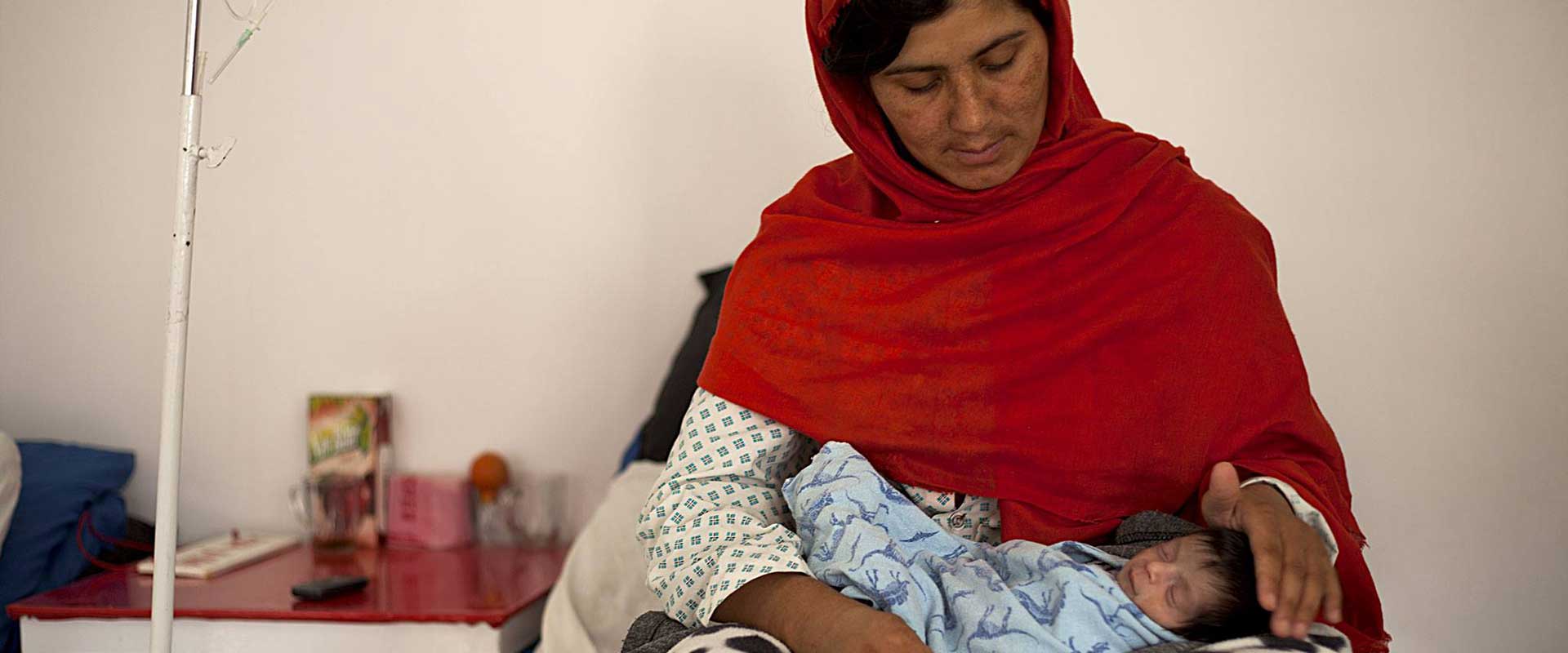 Una madre tiene in braccio il suo neonato nelle corsie del Centro di maternità di Anabah, in Afghanistan
