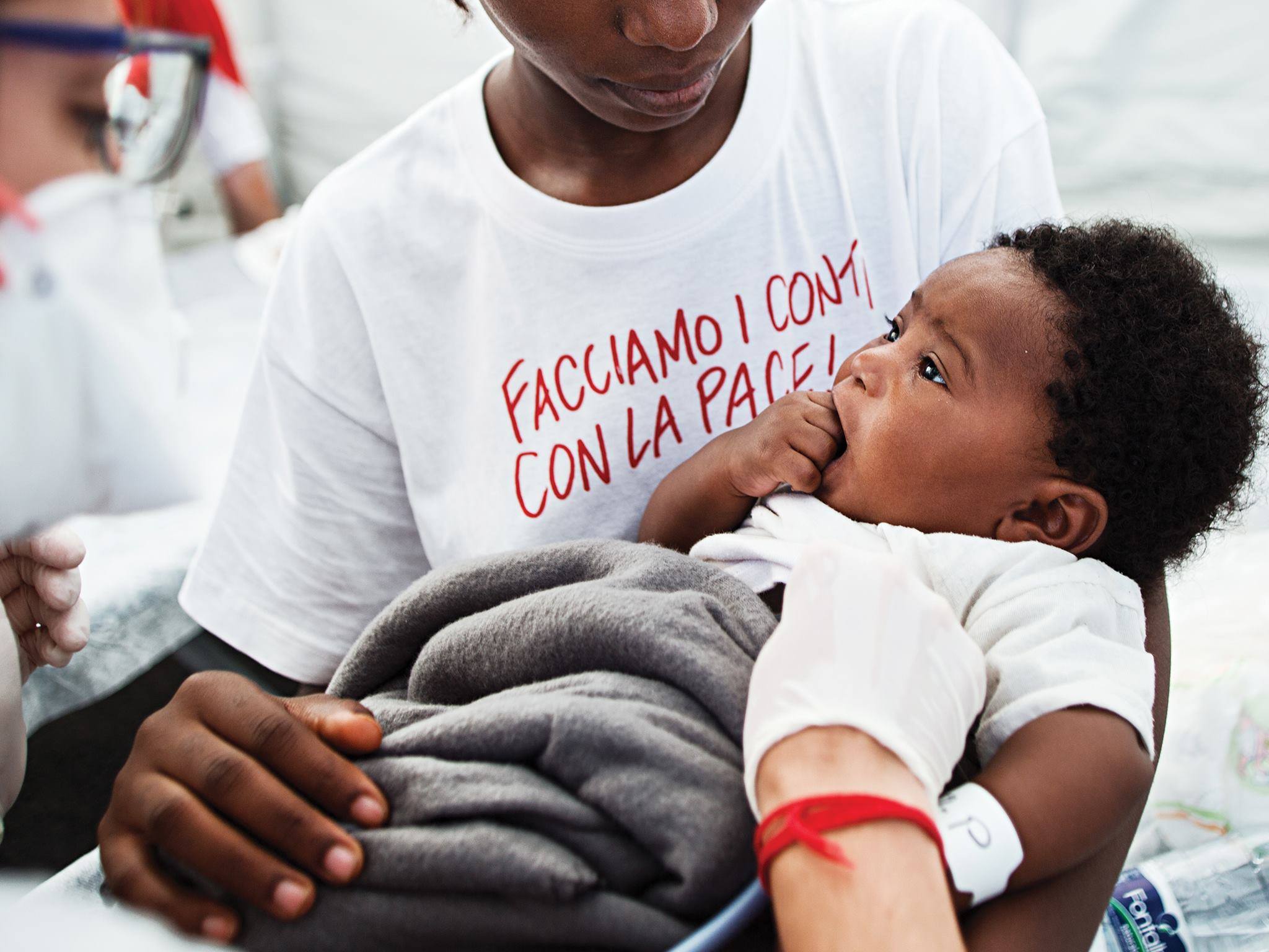 Al porto di Augusta, in Sicilia, una donna tiene in braccio un bambino